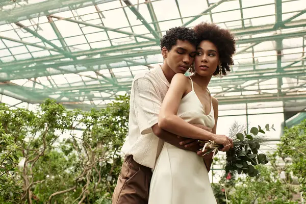 A young couple hugs in lush greenery, radiating love and calm in a serene setting. — Stock Photo