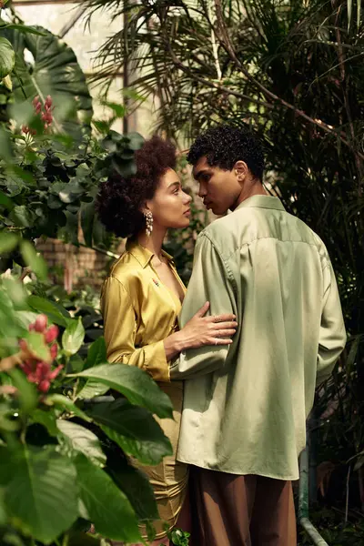 A young couple embraces amidst vibrant greenery, exchanging loving gazes in the greenhouse. — Stock Photo