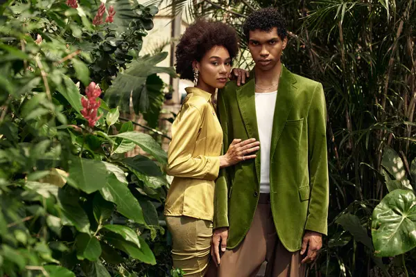 In a lush greenhouse, a young couple shares a loving embrace among vibrant plants and flowers. — Stock Photo