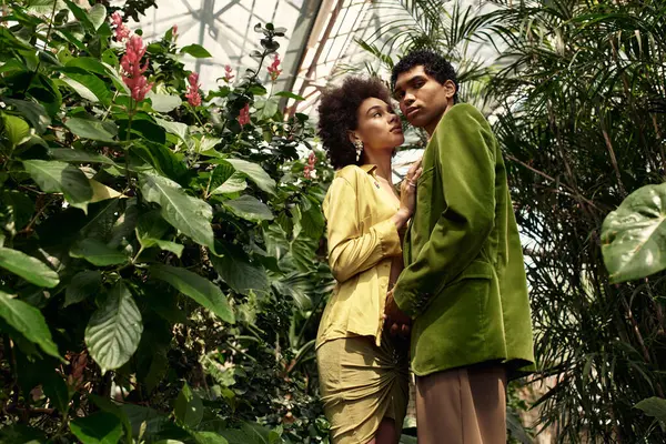 Casal jovem compartilha um momento terno em meio a plantas exuberantes em um belo cenário de estufa. — Fotografia de Stock