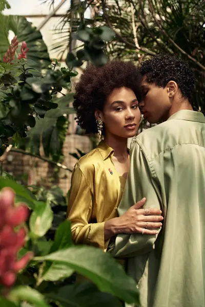 A loving couple embraces in a serene greenhouse filled with lush plants and greenery. — Stock Photo