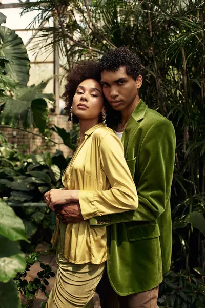 A couple hugs in a greenhouse, surrounded by lush plants, radiating love and togetherness. — Stock Photo