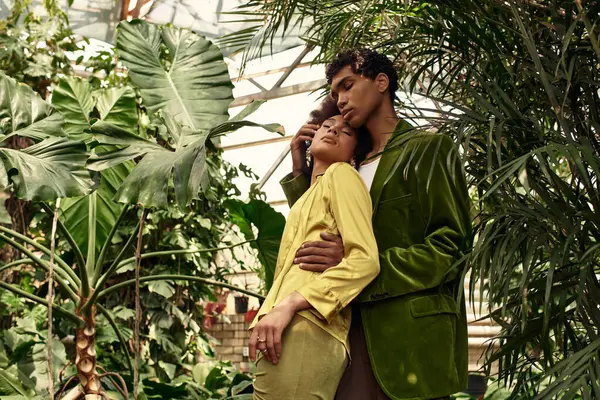 Loving couple enjoys each others embrace surrounded by vibrant plants and fresh greenery. — Stock Photo