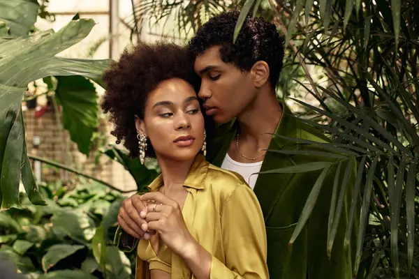 Um casal amoroso compartilha um momento terno cercado por plantas florescentes em um ambiente de estufa. — Fotografia de Stock