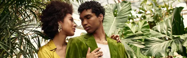 Two young lovers enjoy each others company surrounded by lush plants in a serene greenhouse. — Stock Photo