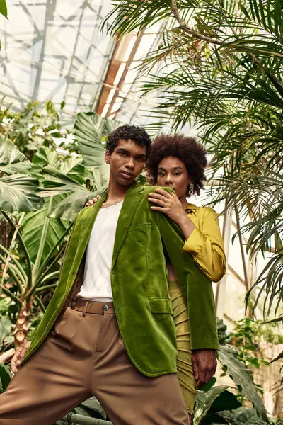 Couple hugs in a vibrant greenhouse, surrounded by lush plants, celebrating their love. — Stock Photo