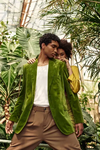 Young lovers embrace in a lush greenhouse, enjoying each others company among thriving plants. — Stock Photo
