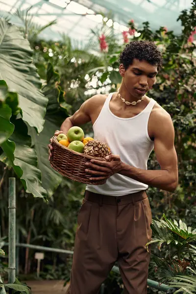 A handsome man enjoys a tender moment amid vibrant plants and fruits in a greenhouse. — Stock Photo
