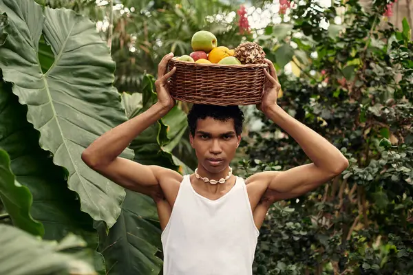 A handsome man gathers ripe fruits amid vibrant greenery, sharing moments of joy in a greenhouse. — Stock Photo