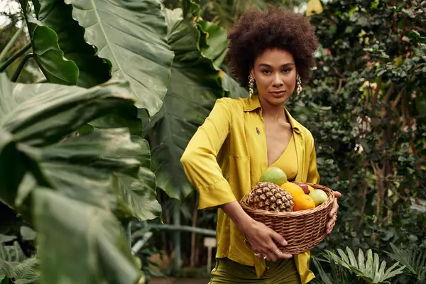 A beautiful woman shares joyful moments, surrounded by lush plants and a woven basket of fruits. — Stock Photo