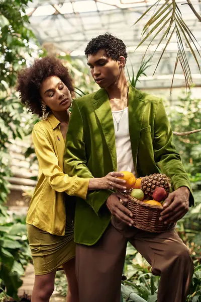 In a lush greenhouse, a joyful couple shares a tender embrace while picking colorful fruits. — Stock Photo