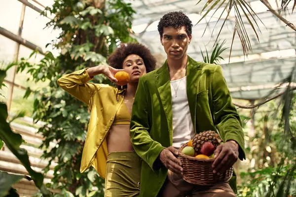 A couple joyfully interacts in a greenhouse filled with vibrant plants, embodying romance. — Stock Photo