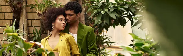 Um jovem casal desfruta de seu amor em meio a plantas exuberantes em uma estufa. — Fotografia de Stock