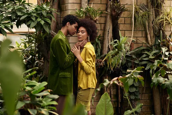 A couple embraces amid lush plants, cherishing their romantic connection in nature. — Stock Photo