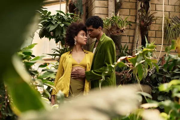 In a vibrant greenhouse, a young couple shares a tender moment surrounded by thriving greenery. — Stock Photo