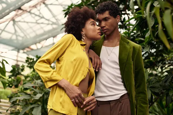 A couple shares an intimate moment among vibrant plants in a beautiful greenhouse setting. — Stock Photo