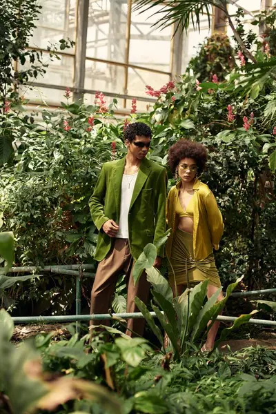 A young couple embraces in a colorful greenhouse filled with lush plants, showcasing their love. — Stock Photo