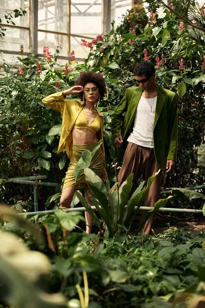 En un invernadero impresionante, una joven pareja celebra alegremente su amor en medio de plantas vibrantes. - foto de stock