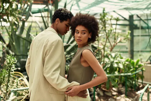 A loving couple connects amidst vibrant plants in a serene greenhouse atmosphere. — Stock Photo