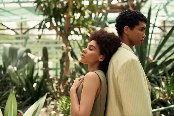 A loving couple shares a moment in a greenhouse surrounded by abundant plants and nature. — Stock Photo