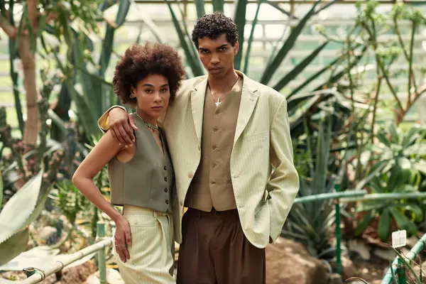 Um jovem casal abraça em meio a plantas florescentes, celebrando o amor e a conexão na natureza. — Fotografia de Stock