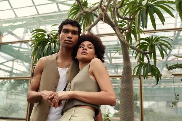 A young couple shares a romantic moment in a lush greenhouse filled with plants. — Stock Photo
