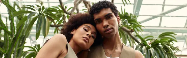 Two young lovers embrace in a lively greenhouse filled with beautiful plants and greenery. — Stock Photo