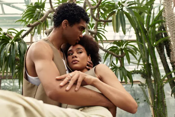 Jovem casal desfruta de um momento terno juntos, rodeado por plantas exuberantes em uma estufa tranquila. — Fotografia de Stock
