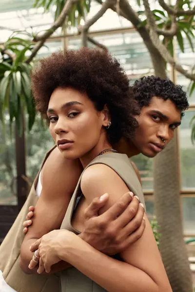 A loving couple shares an intimate moment surrounded by thriving plants and greenery. — Stock Photo