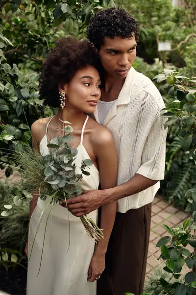 A young couple enjoys their love in a beautiful greenhouse surrounded by greenery and plants. — Stock Photo