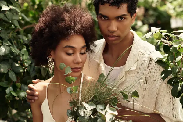A vibrant couple embraces in a greenhouse, surrounded by thriving plants and lush greenery. — Stock Photo