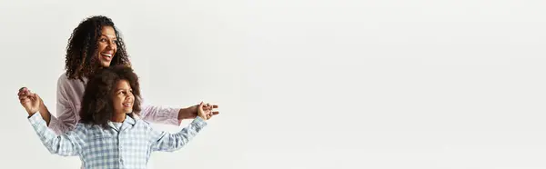 A happy African American mother and daughter wear matching pyjamas in a studio, banner — Stock Photo