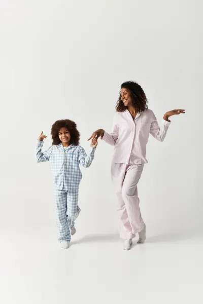 African American mother and daughter in matching pyjamas dancing in studio — Stock Photo