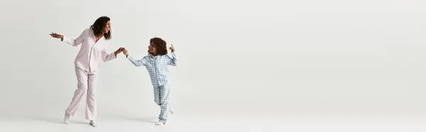 Eine afroamerikanische Mutter und ihre Tochter tanzen zusammen in passenden Pyjamas im Studio, Transparent — Stockfoto