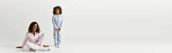 Preto mãe e filha em correspondência PJs, sorrindo calorosamente no estúdio, banner — Fotografia de Stock