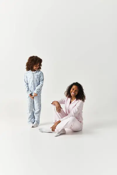African American mother and her daughter wear matching pyjamas. — Stock Photo