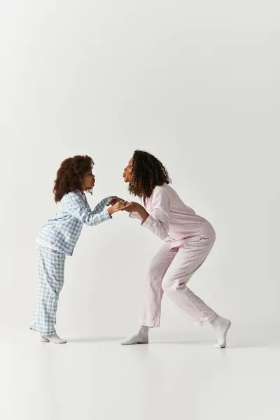 African American Mother and daughter share a tender moment, wearing matching pyjamas in the studio. — Stock Photo