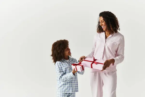 Studio: Black mom and daughter in PJs exchange gifts. — Stock Photo