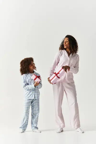 Stylish Black mom and daughter in matching PJs hold gifts — Stock Photo
