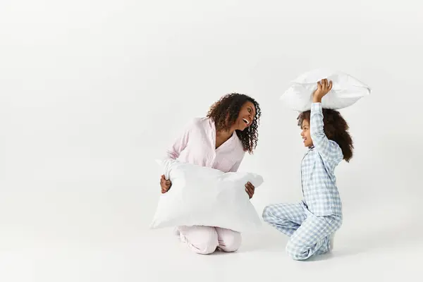Black mother and child in pjs pillow fighting in studio — Stock Photo