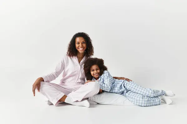 Black mother and daughter in matching PJs, smiling at camera. — Stock Photo