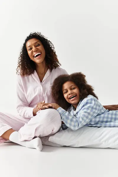 Preto mãe e filha rir em pijama, estúdio cinza. — Fotografia de Stock