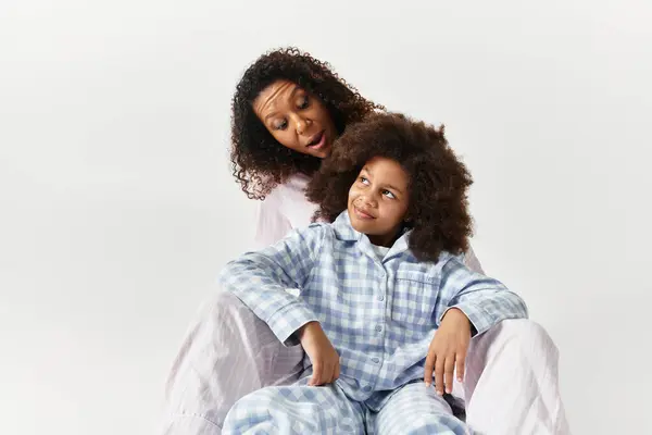 Black mother and daughter in pajamas, studio portrait. — Stock Photo