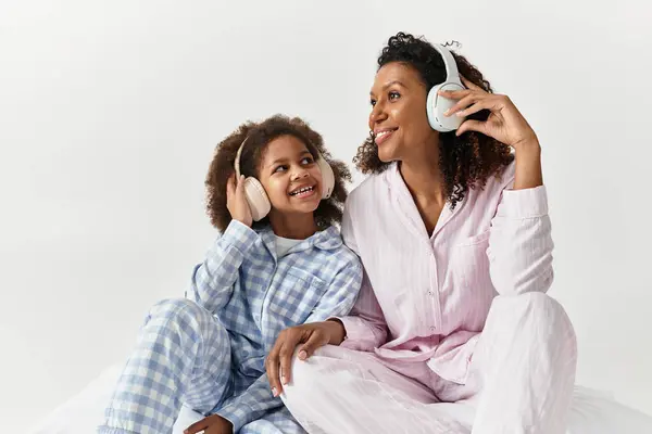 Afroamericani madre e figlia in pigiama si siedono in uno studio, ascoltando musica — Foto stock
