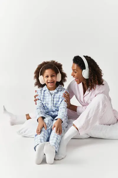 Matching PJs, mom & daughter sing, laugh, and share music. — Stock Photo