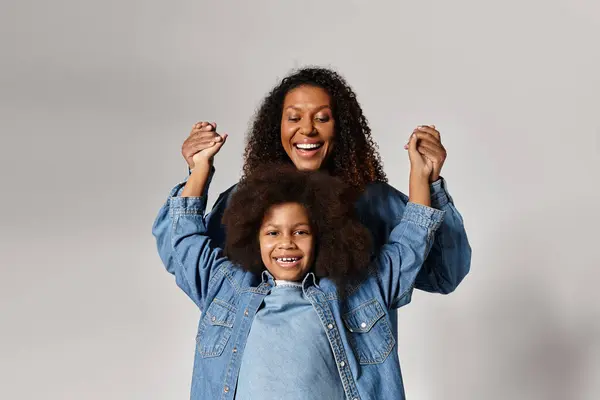 Black mother and daughter hug, denim outfits, big smiles in studio. — Stock Photo