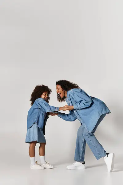 Mãe e filha negra feliz em roupas de ganga, pano de fundo cinza. — Fotografia de Stock