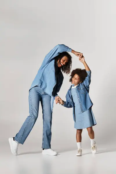Nero mamma e figlia danza, denim rivestito, gioioso momento di famiglia. — Foto stock