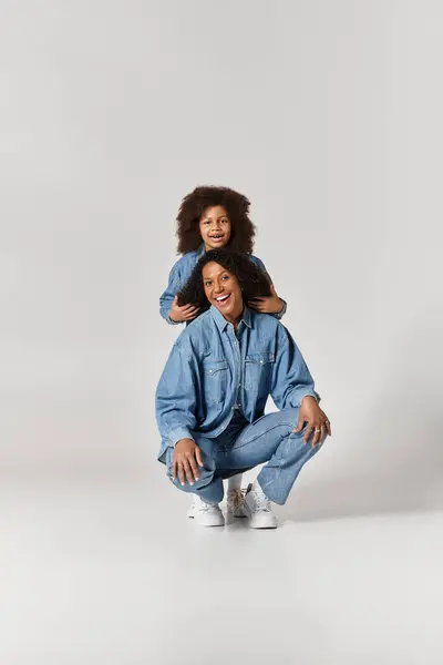 In a fashion moment, a Black mother squats while her daughter embraces her. — Stock Photo