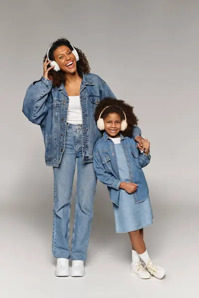 Stylish Black mom and daughter in matching denim clothes pose in studio. — Stock Photo